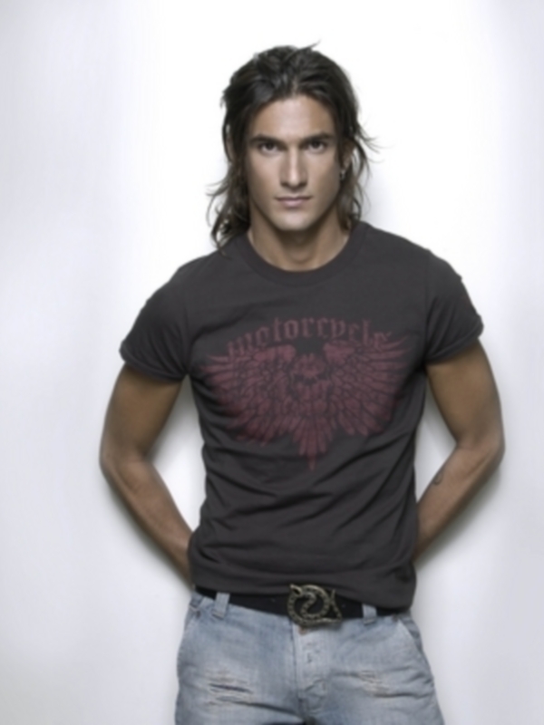 Hombre con camiseta 'motorcycles' y jeans, posando con las manos en los bolsillos.