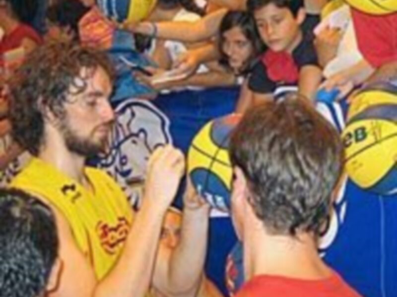 Un grupo de personas interactuando con pelotas de baloncesto en un evento deportivo.