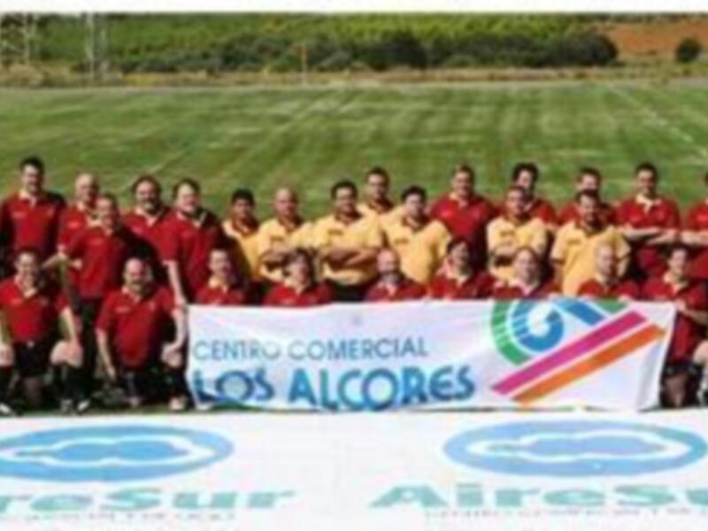 Equipo de fútbol posando en un campo verde con una bandera que dice "Centro Comercial Los Alcores".