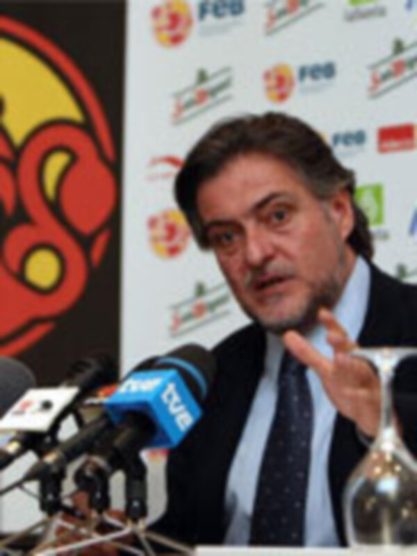 Un hombre hablando en una conferencia de prensa con micros y banderas de España y la UEFA.