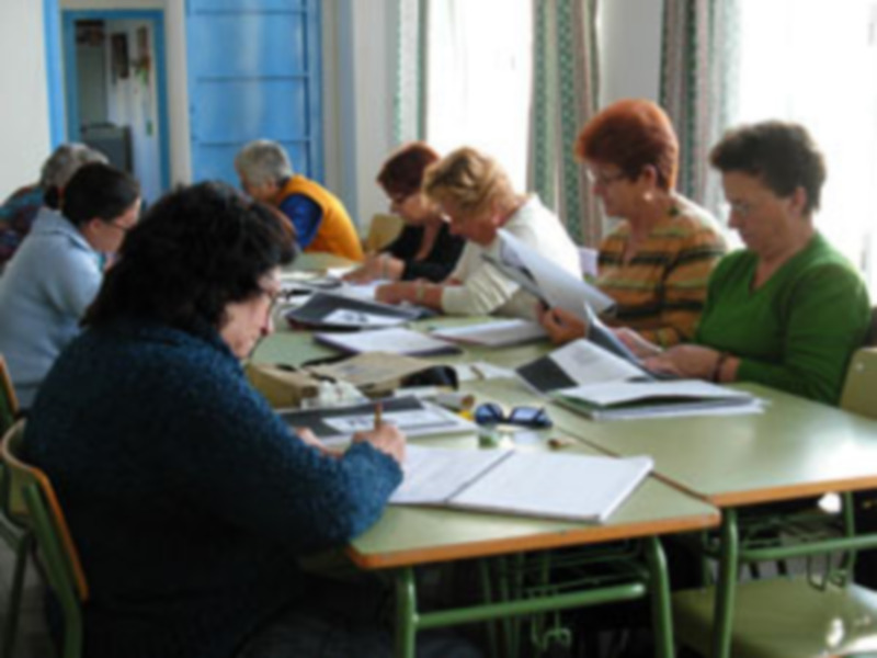 Una clase en un aula con estudiantes sentados en mesas, trabajando y aprendiendo.
