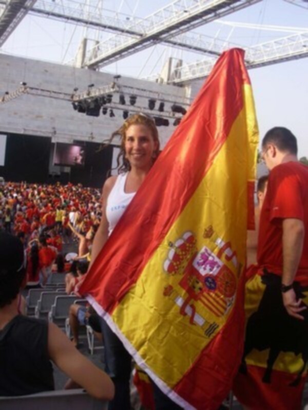 Una mujer sostiene una bandera española en un estadio lleno de espectadores.