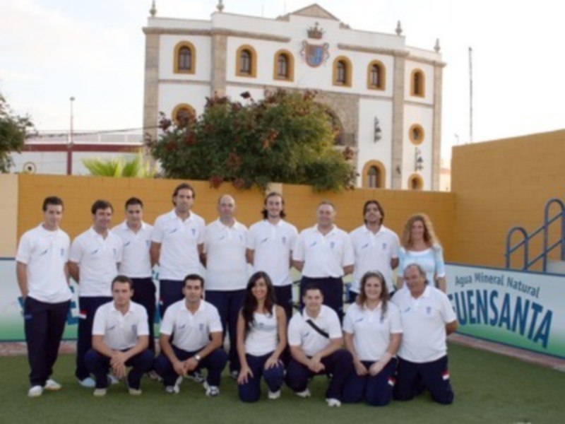 Equipo deportivo posando en el campo de fútbol junto a un edificio histórico.