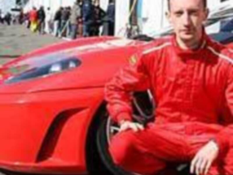 Un piloto de carreras posa junto a un Ferrari en una pista de carreras.