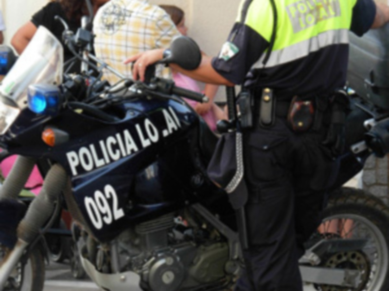 Una motocicleta de Policía Local con el número 092, estacionada junto a un policía en uniforme.
