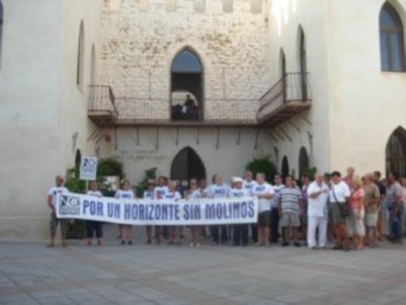 Una multitud con una pancarta que dice "Por un horizonte sin mimos" frente a un edificio histórico con balcones y ventanas.