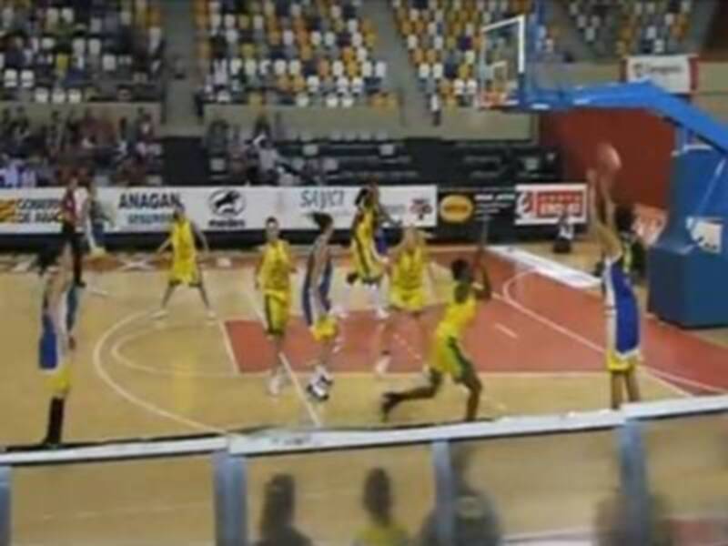 Un partido de baloncesto en un estadio lleno, con jugadores en acción durante el juego.