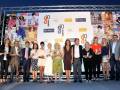 Premios de moda y belleza en una ceremonia nocturna con invitados destacados y carteles promocionales en el fondo.