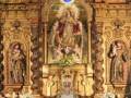 Retablo barroco con imágenes religiosas y flores en el altar.