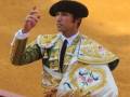 Un torero español con traje tradicional, incluyendo un sombrero de copa y una capa bordada con flores.