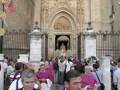 Grupo de personas en trajes frente a la catedral, con una estatua en el interior.