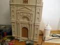 Maqueta de arquitectura clásica en proceso de montaje, con detalles arquitectónicos y herramientas alrededor.