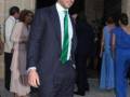 Un hombre en traje y corbata verde en una reunión formal.