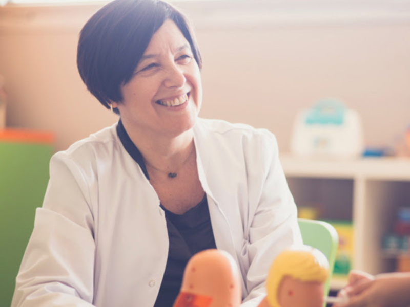 Profesora sonriente en una clase de educación infantil, rodeada de juguetes educativos.