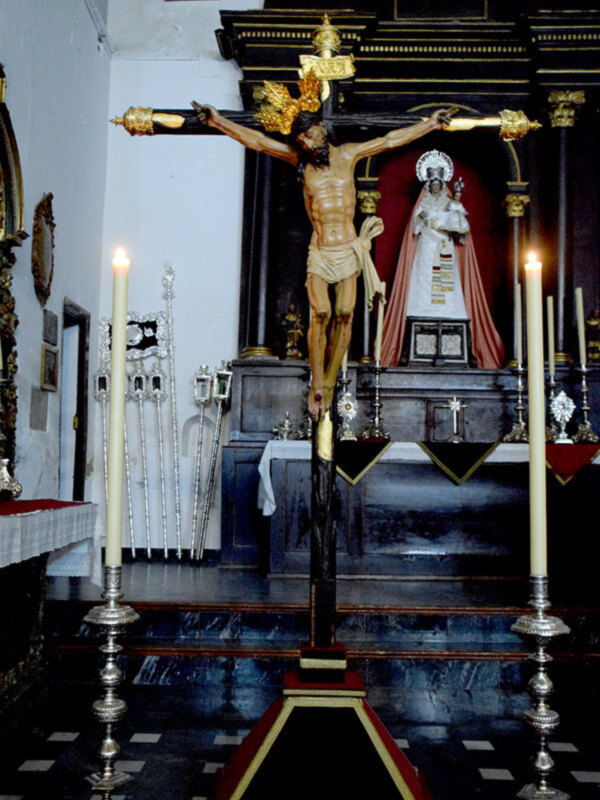 Crucifijo en un altar religioso con candelabros y una imagen de la Virgen María.