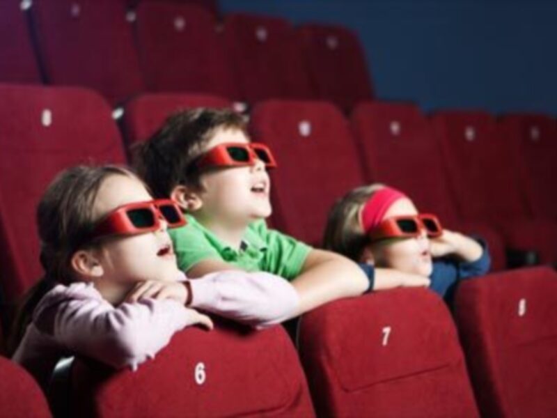 Niños viendo una película en 3D con gafas especiales en el cine.