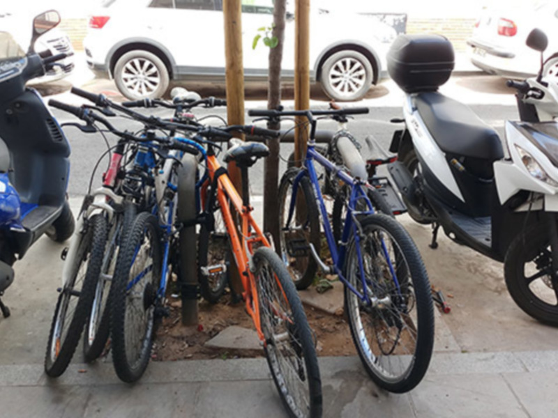 Bicicletas aparcadas junto a una moto en un aparcamiento.