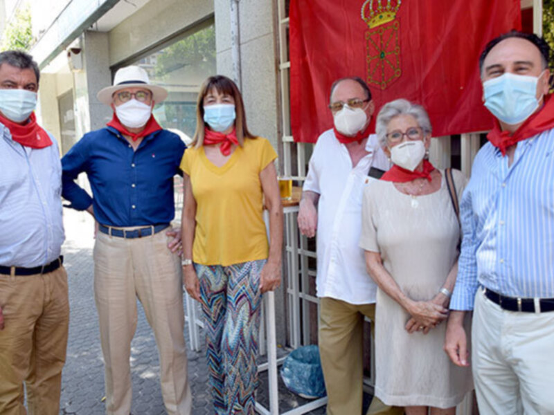 Grupo de personas con bufandas rojas y máscaras faciales, posiblemente en un evento o celebración.