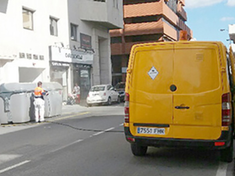 Vehículo amarillo con matrícula 87551 FH4, estacionado en una calle con edificios al fondo.