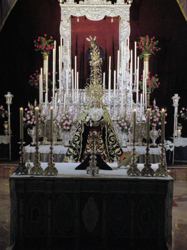 Altar con estatua central, flores y velas en iglesia.