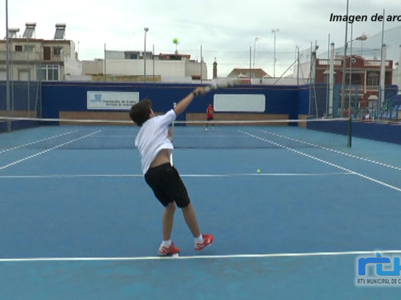 Un niño juega al tenis en una cancha azul con una casa en el fondo.