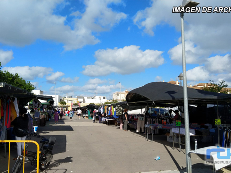 Mercado de abastos en un día soleado con tiendas y puestos de venta.