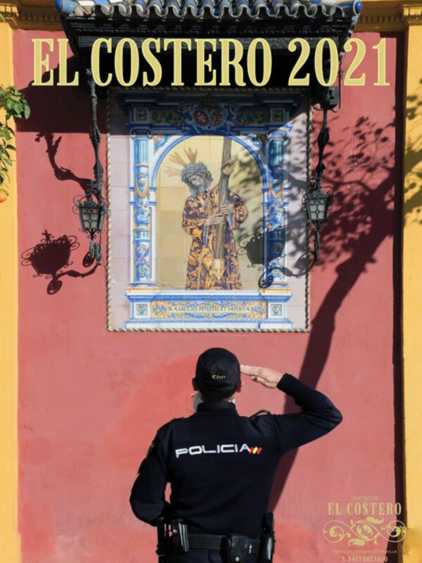 Un policía mira una imagen de un rey en una ventana de un edificio con murales. La imagen se titula "El Costero 2021".