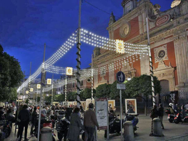 Imaginación de una multitud de personas caminando por la calle principal, con luces navideñas colgadas en forma de estrellas y un edificio histórico al fondo.