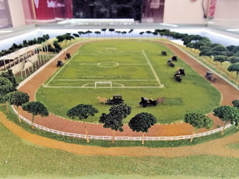 Modelo de un estadio deportivo con un campo de fútbol y una pista de atletismo.