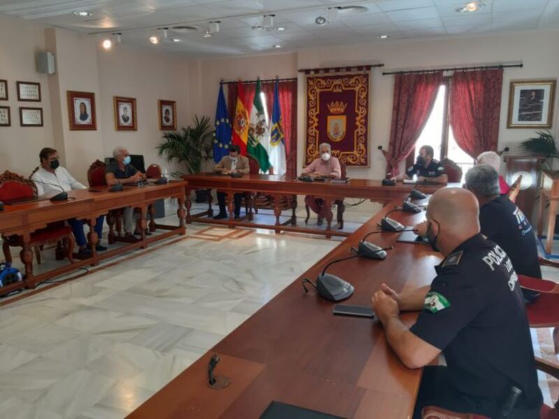 Reunión de autoridades en una sala oficial con banderas y emblemas, probablemente un consejo o reunión de gobierno local.