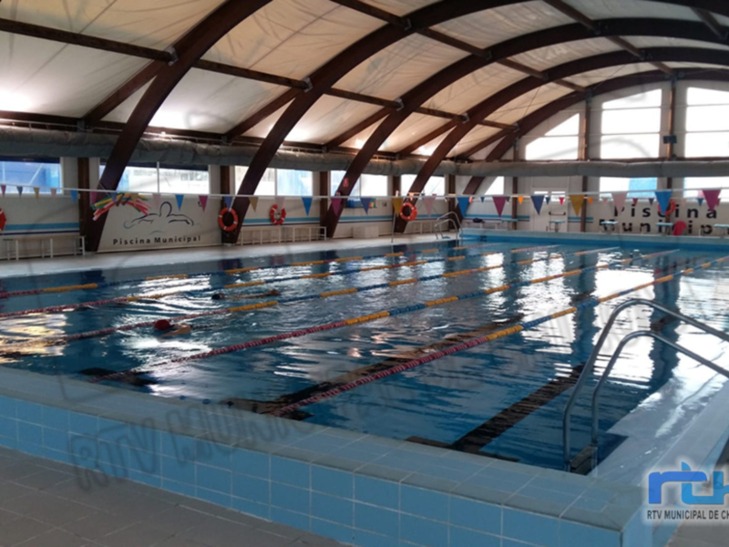 Piscina Municipal con azulejos azules, rampas de acceso y banderas decorativas.