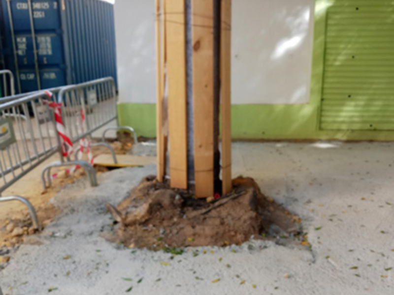Instalación de poste en construcción, cerca de contenedores y valla de seguridad.