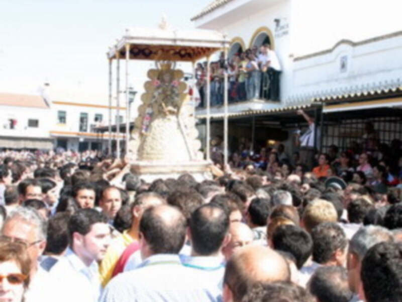 Una multitud de personas en un evento al aire libre, con un escenario en el centro y una estructura dorada en el fondo.