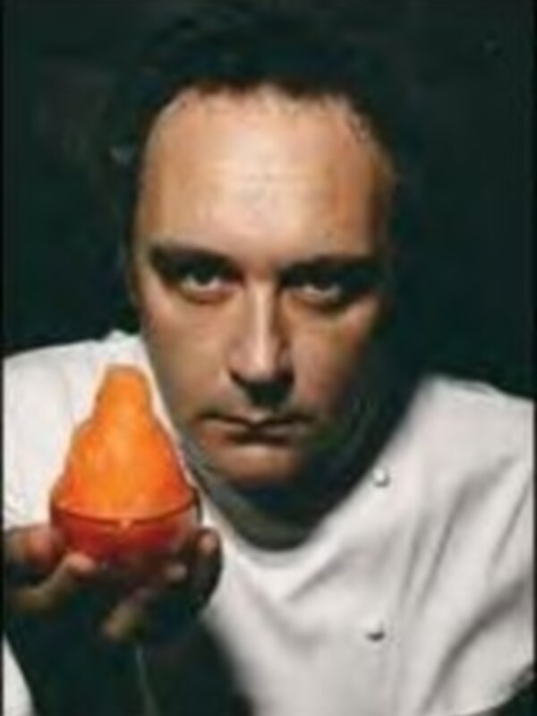 Un hombre sostiene una figura de un conejo hecho de una fruta, posiblemente una naranja, con un fondo oscuro.