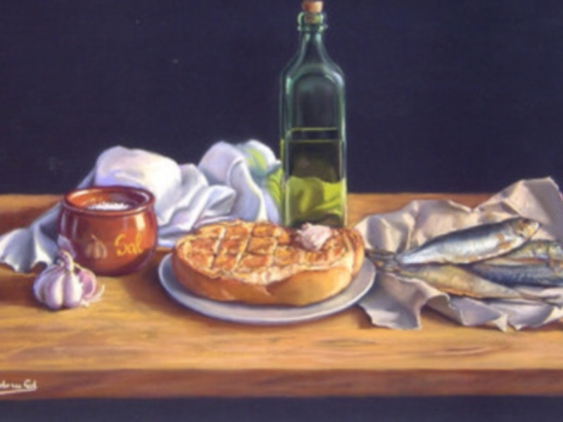 Un cuadro que muestra una mesa de madera con un pan recién horneado, una botella de aceite de oliva, una taza con un líquido marrón y algunas verduras.