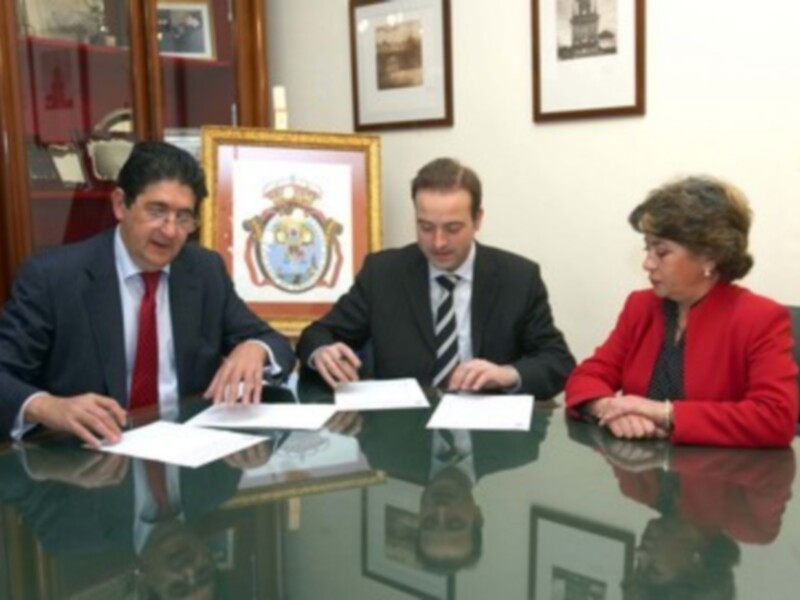 Tres personas en trajes sentadas en una mesa de oficina, discutiendo documentos.