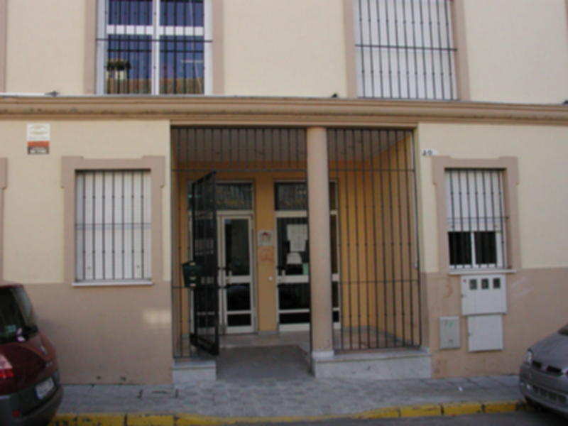 Entrada principal de un edificio con puerta de metal y ventanas con barrotes.