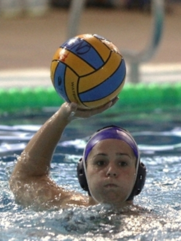 Una jugadora de waterpolo sostiene una pelota azul y amarilla en la superficie del agua.