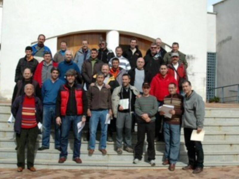 Grupo de personas posando en la entrada de un edificio, con una variedad de ropa casual y algunos portando documentos.