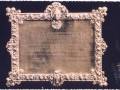 Esta es una placa de bronce con un marco ornamental. La inscripción en español menciona una solicitud al alcalde por la colonización de un lugar llamado "La Colonia de San Francisco Javier Marquina". La fecha mencionada es el 15 de noviembre de 1942.