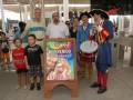 Un hombre vestido como un marinero colonial toca un tambor mientras niños y adultos observan. La imagen está en la Isla Mágica, donde se celebra el evento de los 13.000.000 visitantes.
