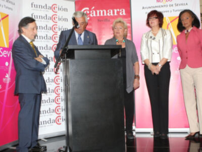 Presentación en la Fundación Cámara de Sevilla, con un hombre hablando al micrófono y cuatro mujeres detrás de él.