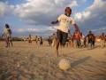 Niños jugando en la playa con una pelota.