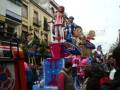 Un gran carnaval con figuras gigantes y personajes divertidos en una calle.