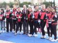 Equipo femenino de remo celebrando una victoria en un evento deportivo, posando con medallas y sonriendo.