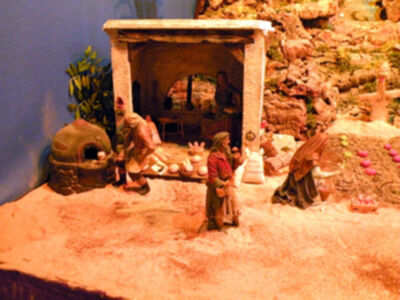 Un pequeño pueblo en miniatura con figuras de personas y animales, rodeado por rocas y vegetación.