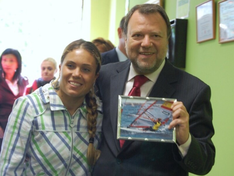 Persona conmemorando con un certificado junto a otra persona en un entorno formal.