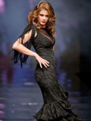 Una modelo presenta un vestido negro de encaje con volantes en la falda. La imagen se centra en el detalle del vestido y la postura elegante de la modelo.