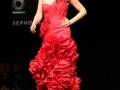Modelo con vestido rojo de una hombro en desfile de moda.