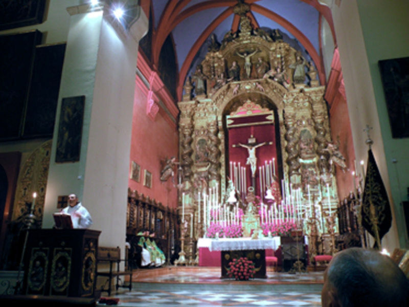 Interior de una iglesia con un altar elaborado y un crucifijo en el centro.